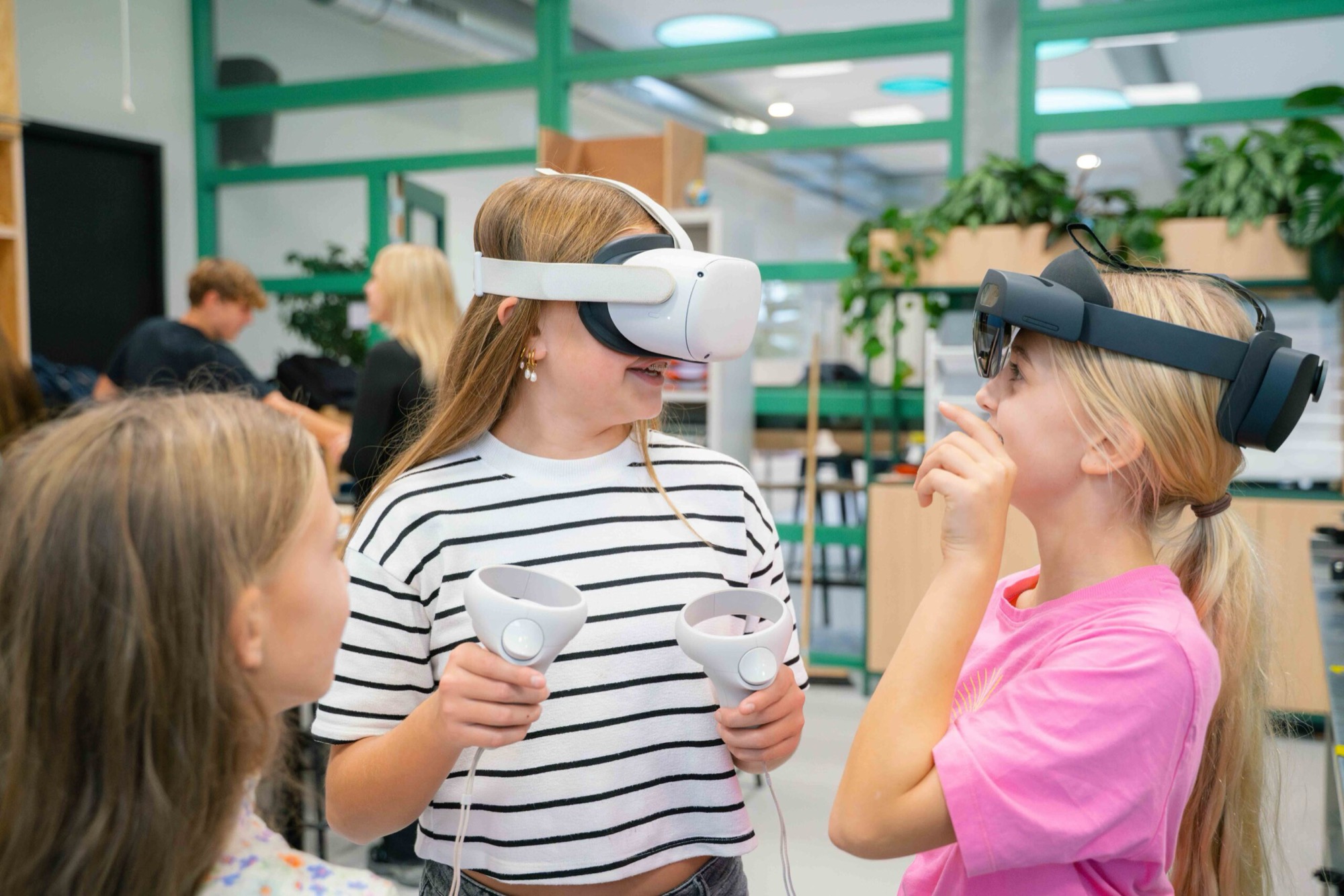 Leerlingen proberen lachend een VR-bril uit in een licht, groen ingericht lokaal.